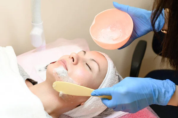 The process of applying a moisturizing mask to the face in a spa salon, applying the mask with a spatula.