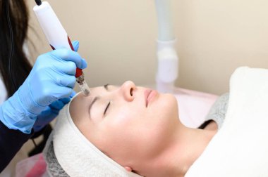 A cosmetologist performs a mesotherapy rejuvenation procedure with the help of dermapen, a visit to a cosmetologist. clipart
