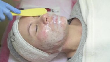 A clients visit to a cosmetologist, moisturizing the face with a cosmetology mask, applying a mask to the face, video 4k.