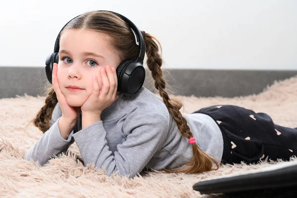 Mała Dziewczynka Leży Kanapie Słucha Muzyki Słuchawkach Portret Dziecka Słuchawkami — Zdjęcie stockowe