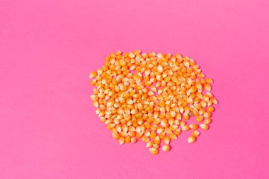 Pembe zemin, kopyalama alanı ve üst görünüm üzerinde patlamış mısır yapmak için mısır çekirdekleri.