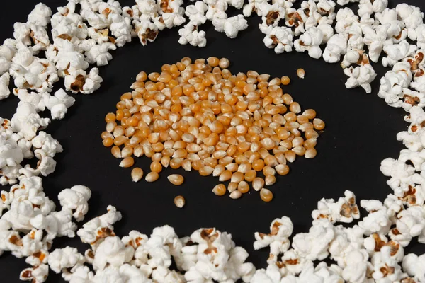 Hromada Kukuřičných Zrn Uprostřed Připraveného Kruhu Popcornu Popcorn Černém Pozadí — Stock fotografie