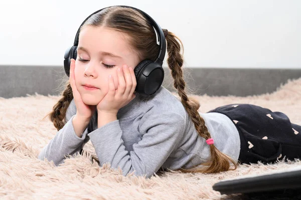 Mała Dziewczynka Leży Kanapie Słucha Muzyki Słuchawkach Portret Dziecka Słuchawkami — Zdjęcie stockowe