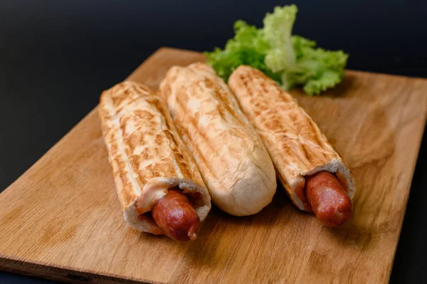 Trzy Francuskie Hot Dogi Drewnianej Desce Czarnym Tle Fast Food — Zdjęcie stockowe