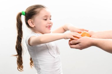 Küçük bir kıza beyaz arka planda mandalina verilir, bir çocuğa mandalina, beyaz arka plan ve kopyalama alanı verilir..