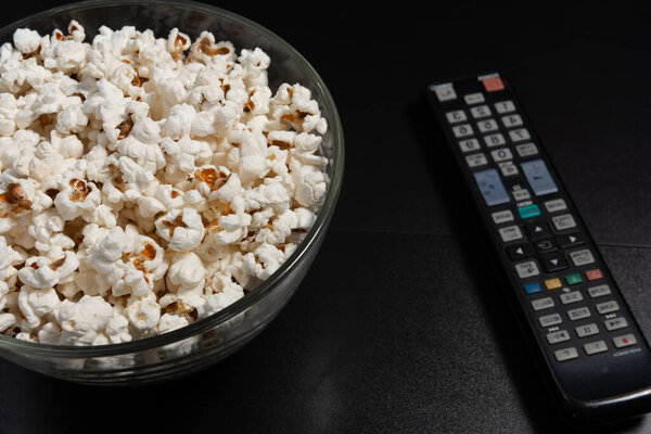 Попкорн пластины и телевизор пульт дистанционного управления на черном фоне, блюдо кукурузы.