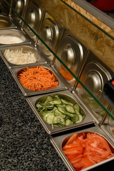 Fast food restoranındaki bir çalışma masasının yüzeyindeki hazır sebzeler için aletler, kaselerde doğranmış sebzeler ve mayonez..