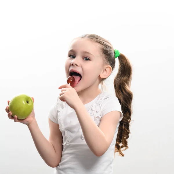 Malá Holka Olizuje Lízátko Drží Jablko Ruce Koncept Zdravého Nezdravého — Stock fotografie