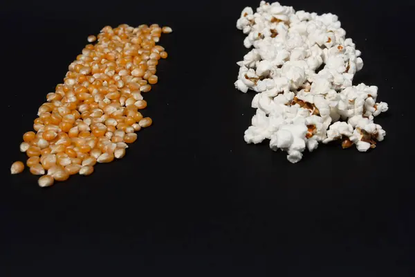 Eine Reihe Fertiges Popcorn Und Eine Reihe Maiskörner Auf Schwarzem — Stockfoto