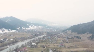 Ukrayna 'daki bir Karpatlar köyünün en üst görüntüsü, ilkbaharın başlarında dağlarda, 4k drone videosu.