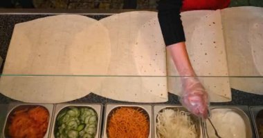 Shawarma yemeklerinin en üst görüntüsü. Zaman ayarlı hızlandırıcı ellerle. Eller restoranda pide ekmeğine sos ekler..