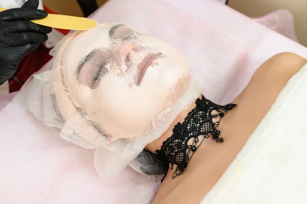 女の子の顔の乾燥した敏感肌のためのケア製品 女の子の顔にガーゼでクリーム — ストック写真