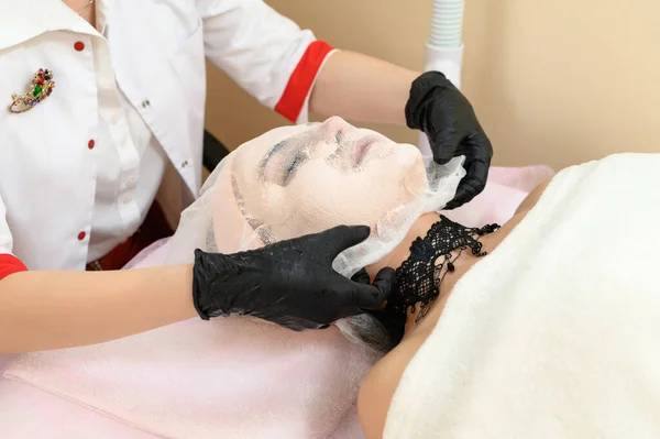 美容师用手 美容术和专业的面部护理 从病人脸上取出用奶油做的纱布 — 图库照片