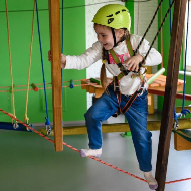 Mutlu kız kabloyu geçiyor, oyun odasında aktif eğlence, çocuğun fiziksel gelişimi için teleferik..