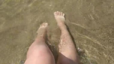 Deniz kıyısında çıplak dişi bacakları, temiz ve berrak deniz suyuyla yıkanır..