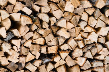 Kesilmiş odun bir konteynırda dikey olarak istiflenir. Kahverengi ve turuncu renklerde kesilmiş yakacak odunları olan doku..