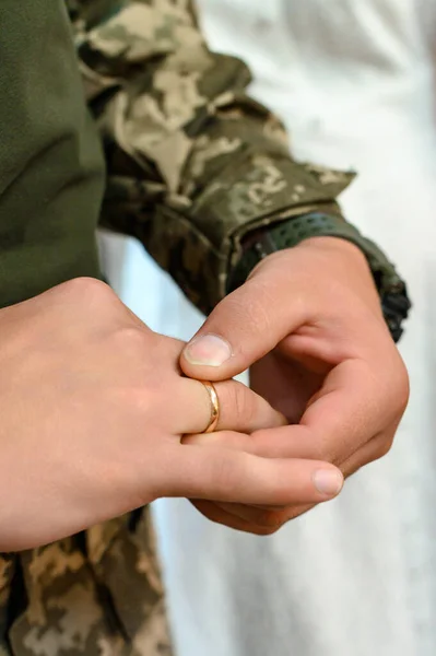Grooms wear their wedding rings on their fingers, wedding rites and customs. Groom in military uniform.