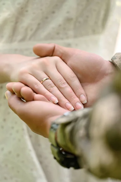 Hands of the bride and groom with rings on their fingers close-up, wedding day. Groom in military uniform.