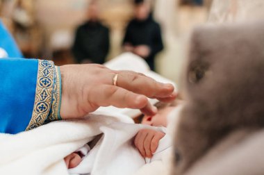 Rahip, çocuğun vaftiz ayinini gerçekleştirir ve bacağını kutsal mira ile kutsar. Hristiyan vaftiz ayini..