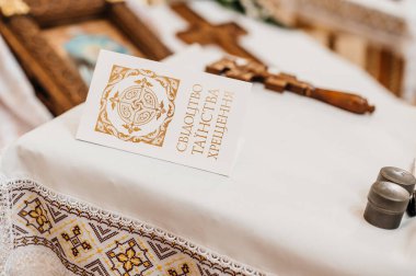 Bir çocuğun vaftiz sertifikası ve içinde haç bulunan küçük gümüş kavanozlar, kilise ayinlerinin unsurları..