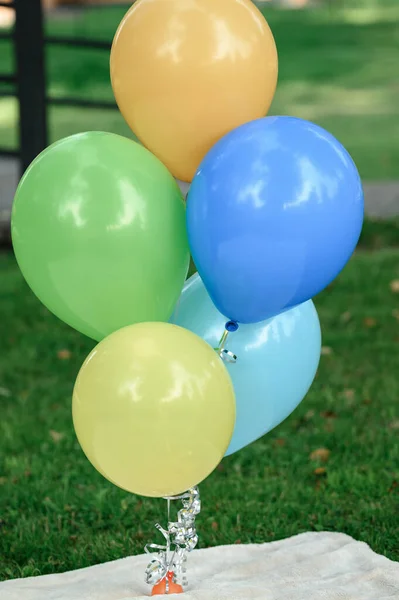Colored helium balloons on green grass background, festive balloons.