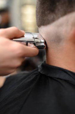 Berber, başındaki kısa saç kesimi sırasında şakağı kablosuz bir budayıcıyla tıraş eder..