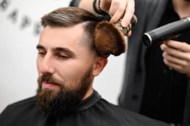Kuaför saç kesimi sırasında saçı fırça ve soğuk kuru havayla süpürür..