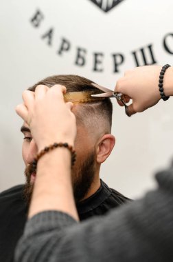Saç kesimi ve kafa hatlarının makas ile hizalanması. Berber dükkanında kısa saç kesimi..