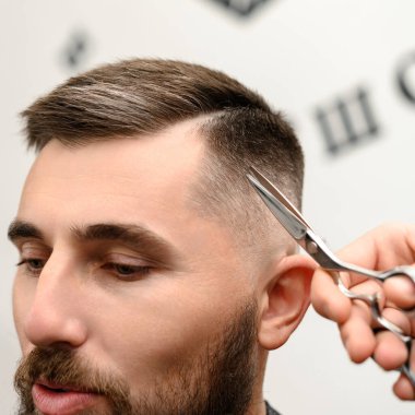 Saç kesimi ve kafa hatlarının makas ile hizalanması. Berber dükkanında kısa saç kesimi..