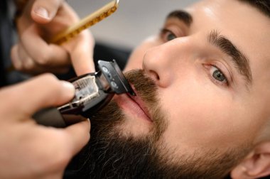 Bir berber, beyaz bir müşteri bıyığını budayarak buduyor..