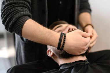 Berber masaj yapar ve nemlendirici yağ sürdükten sonra erkek müşterinin sakalını ovar.