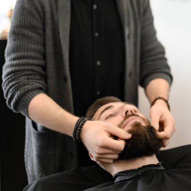 Berber masaj yapar ve nemlendirici yağ sürdükten sonra erkek müşterinin sakalını ovar.