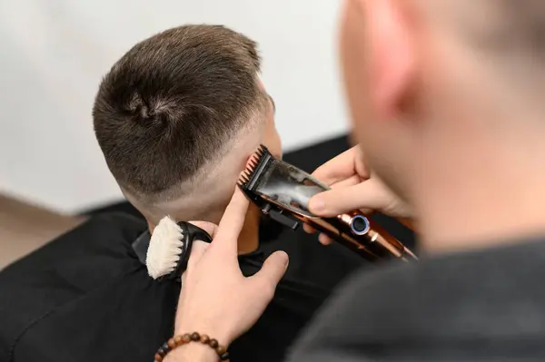 Haircut and alignment of the head contour with a hair clipper and trimmer. Short haircut in the barbershop.