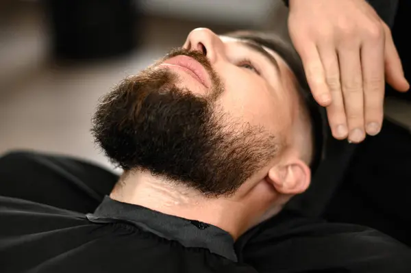 Barber applies shaving gel to the face of a bearded customer