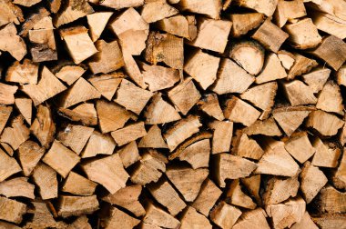 Kesilmiş odun bir konteynırda dikey olarak istiflenir. Kahverengi ve turuncu renklerde kesilmiş yakacak odunları olan doku..