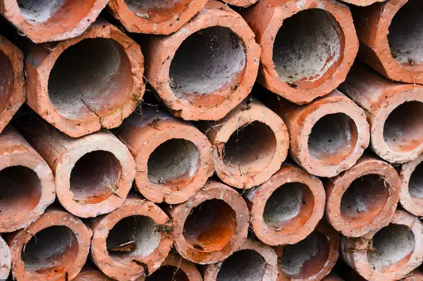 Drainage old clay pipes for sewage stacked in a texture with holes close up