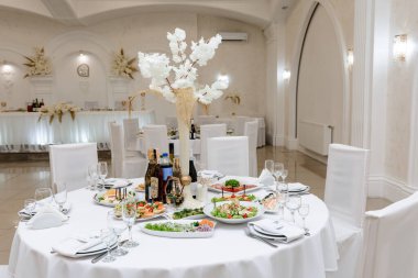 Ivano-Frankivsk, Ukrayna 8 Eylül 2023: Restorandaki festival masasının dekorasyonu ve servis edilmesi, beyaz masa örtüleri ve hazır atıştırmalıklar ve içecekler.
