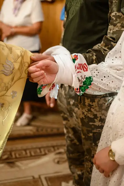 A wedding embroidered towel at a Ukrainian wedding,hands tied with a wedding towel. Groom in military uniform.