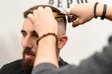 Saç kesimi ve kafa hatlarının makas ile hizalanması. Berber dükkanında kısa saç kesimi..