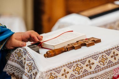Rahibin eli İncil 'in üzerinde, haç da onun yanında, kilise ayini unsurları..