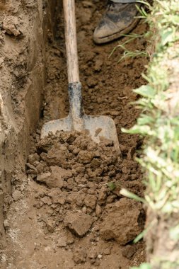 Bir adam kanalizasyon ve kanalizasyon için siper kazıyor..