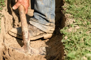 Bir adam kanalizasyon ve kanalizasyon için siper kazıyor..