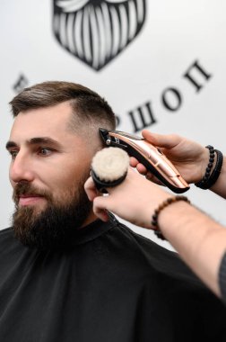 Bir berber berber dükkanında sakallı bir adamı keser. Kesici ile müşterinin kısa saç kesimi.