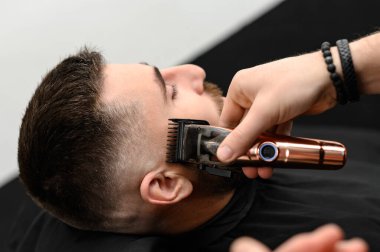 Berber dükkanında bir beyefendinin sakalını makasla kesmek. Müşteri için sahibinin sakalının kenarlarını kısaltıyorum..