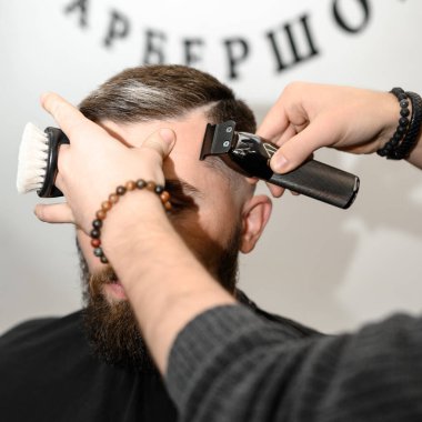 Saç kesimi ve kafa hatları saç makasıyla ve budayıcıyla aynı hizada. Berber dükkanında kısa saç kesimi..