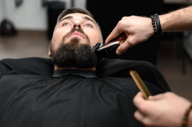 Berber dükkanında bir beyefendinin sakalını makasla kesmek. Müşteri için sahibinin sakalının kenarlarını kısaltıyorum..