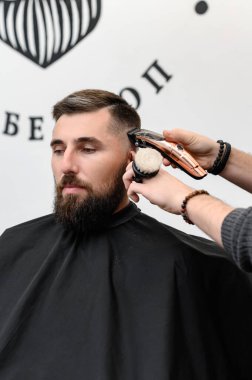 Bir berber berber dükkanında sakallı bir adamı keser. Kesici ile müşterinin kısa saç kesimi.