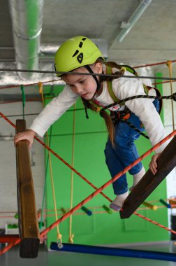 Kız dikkatle ve dikkatlice oyun odasındaki kablodan geçiyor, çocuklar için aktif bir eğlence..