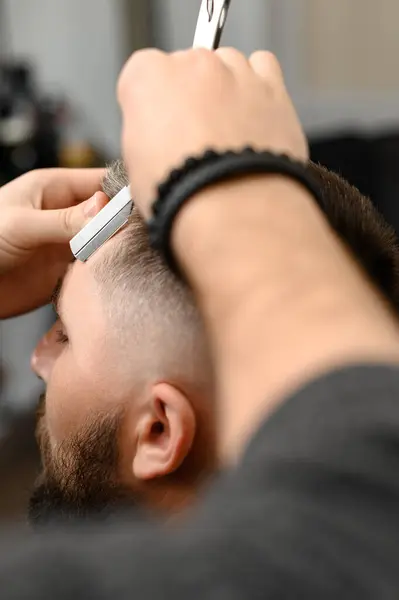 The barber makes the outline with a dangerous razor during the undercut haircut