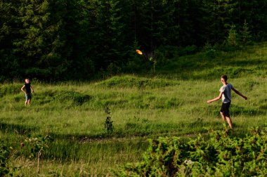 Anne ve oğulları frizbi oynuyor, anne ve çocukların dağlarında aktif eğlence..